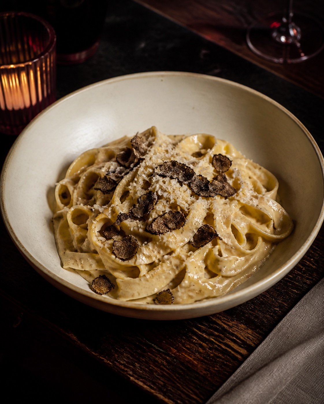 Tagliatelle in a cream ceramic bowl topped with fresh truffle